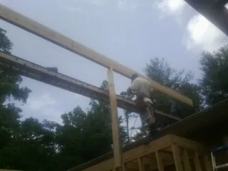 Carpenter setting a ridge beam over a new addition frame — Ice Dam Removal by Roofing Brothers in Maxton
