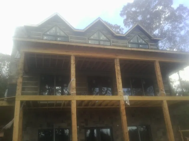 Dormers and porch framing on a large log home under construction — Roof Coating work by our crew in Maxton