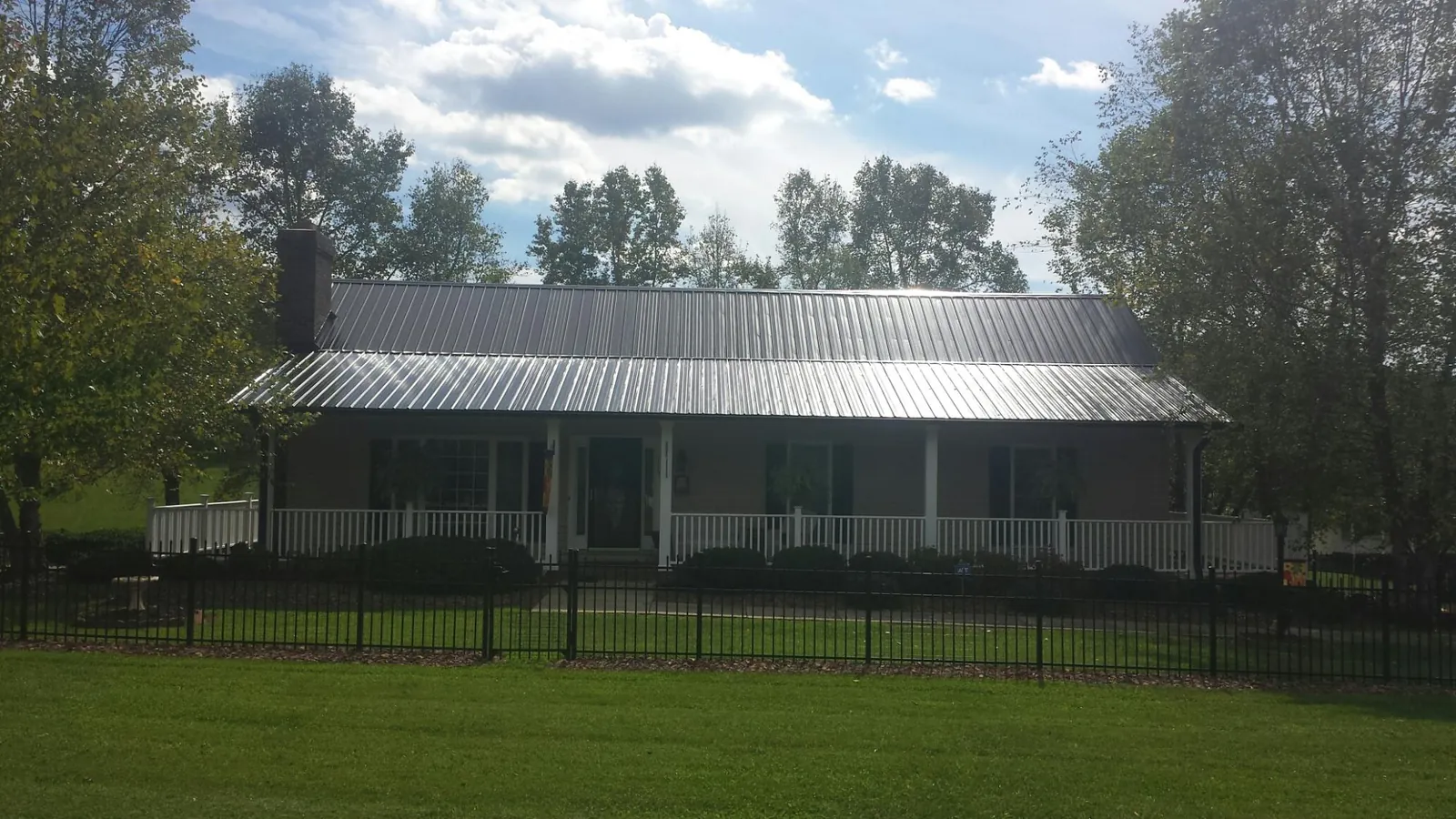 Gray metal roof on a brick ranch with a full width front porch — Gutter Guard Installation work by our crew in Maxton