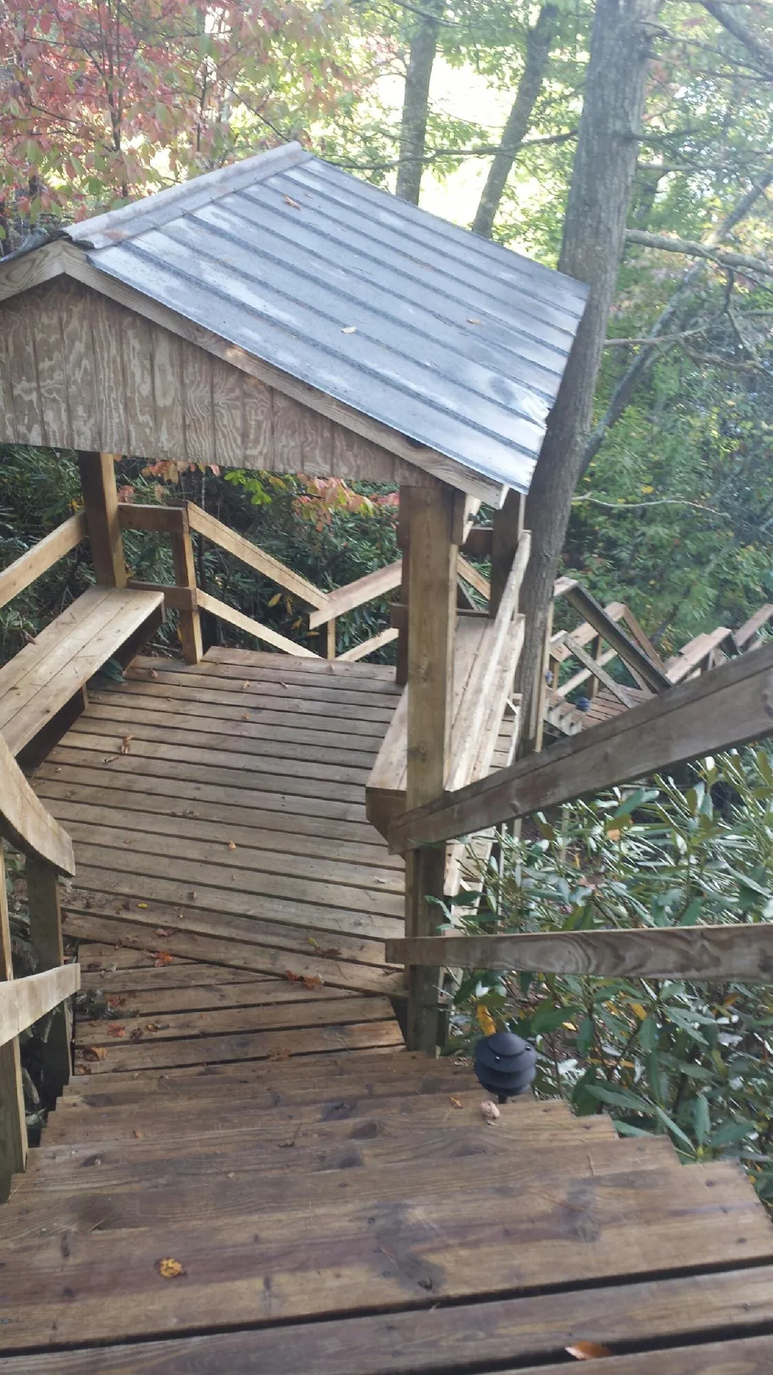 Metal roofed shelter over wooden steps on a wooded walkway — Skylight Repair & Installation work by our crew in Maxton