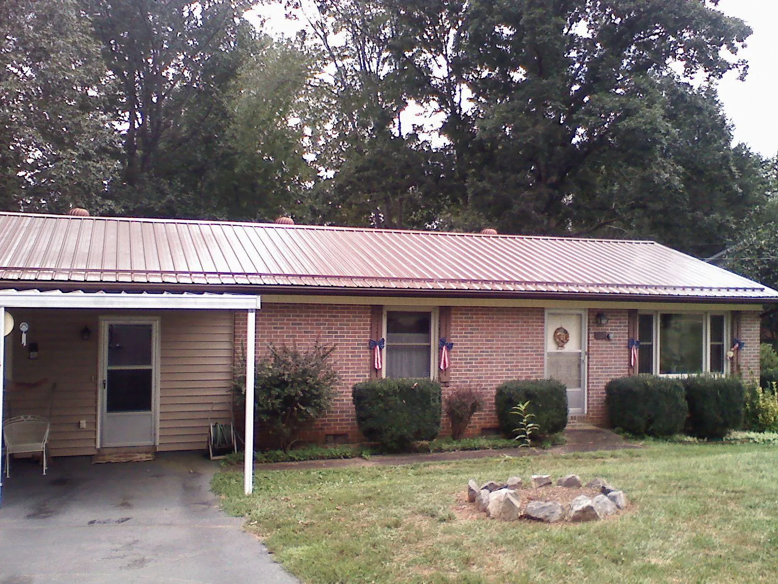 Bronze metal roof and carport on a brick ranch home — Roof Repair work by our crew in Maxton