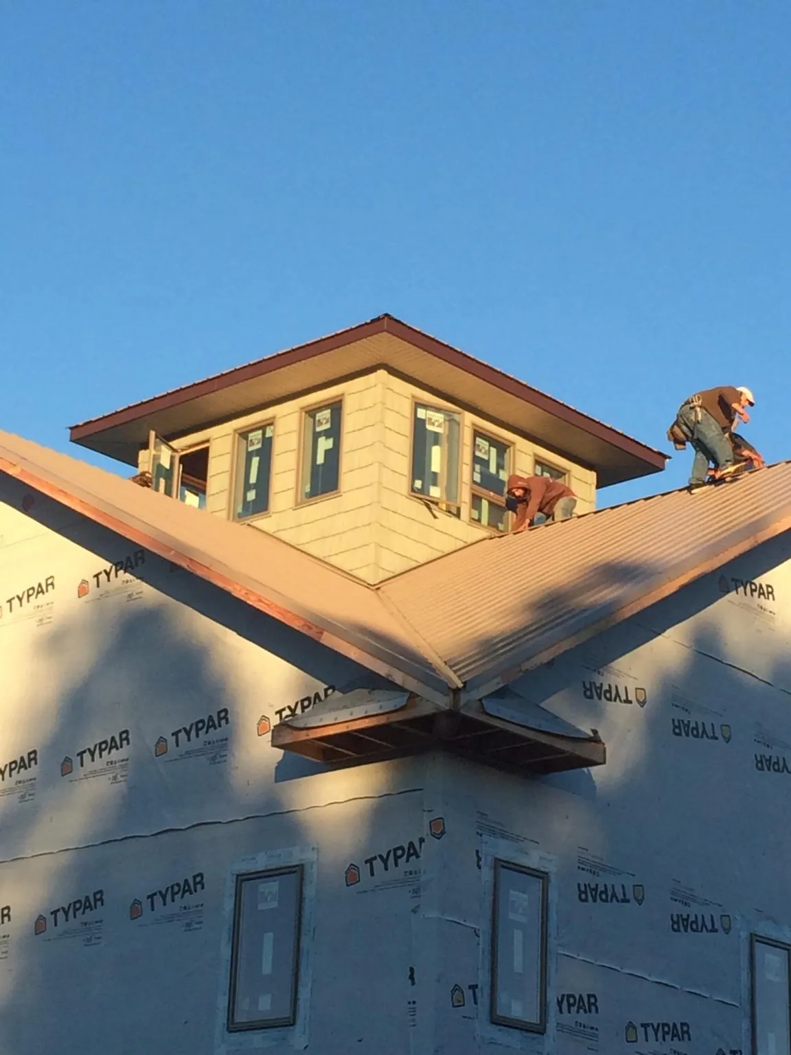 Roofers working around a rooftop cupola on a new metal roof at sunset — Roof Waterproofing in Maxton by Roofing Brothers